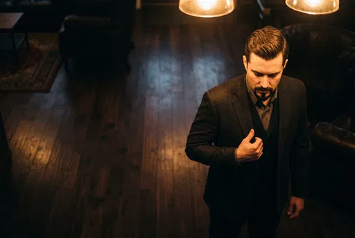 Dapper Man Adjusting Suit Lapel Indoors