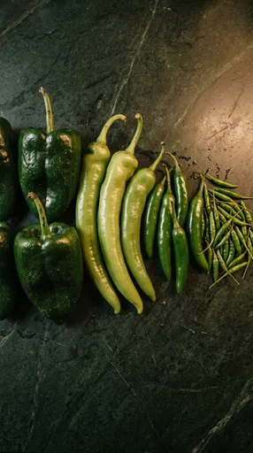 Assorted Green Chili Peppers on Dark Stone