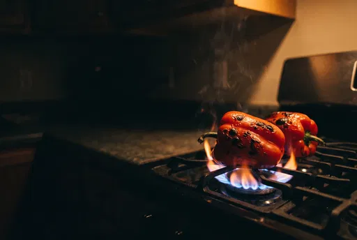 Red Bell Peppers Charring Over Stove Flame