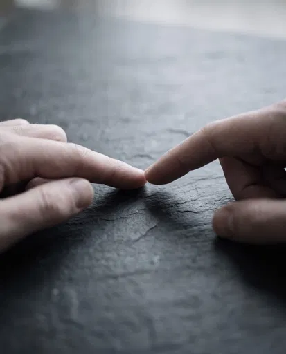 Fingertips Touching on Dark Slate
