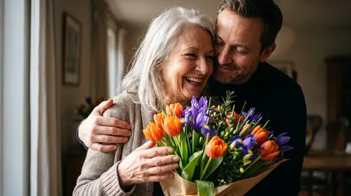 Adult Son Hugging Senior Mother With Flowers