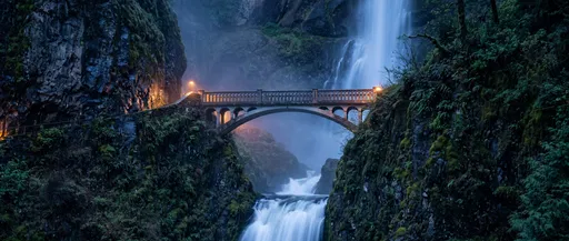 Illuminated Stone Bridge Over Twilight Waterfall