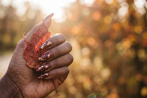 Hand With Burgundy Nails Holding Autumn Leaf