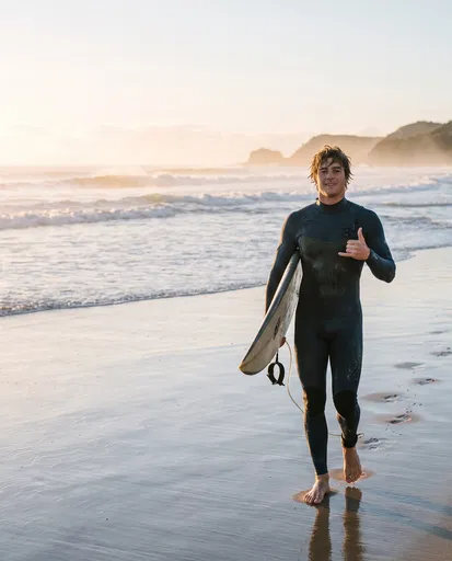 Surfer Walking on Beach at Sunrise