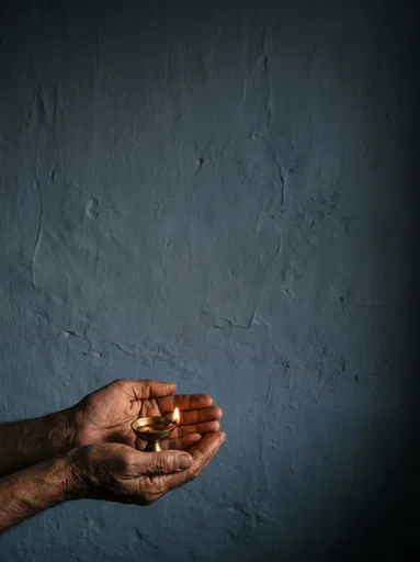 Weathered Hands Cradling Lit Brass Lamp