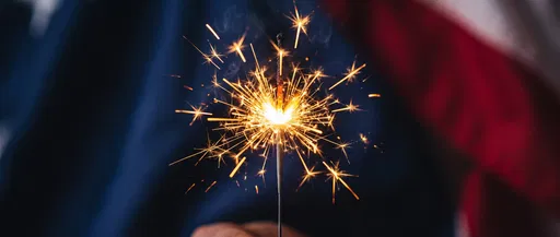 Lit Sparkler Against Blurred Patriotic Backdrop