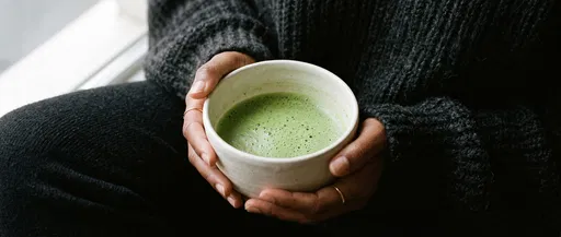 Hands Holding Ceramic Bowl of Matcha Tea