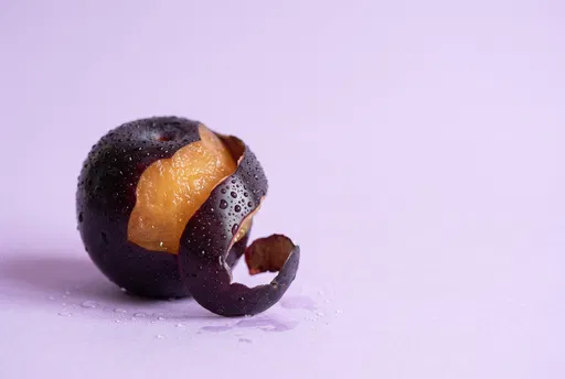 Peeled Black Plum on Lavender Background